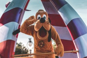 pexels-photo-3411134-3411134 Playful Pluto character waving during a sunny Orlando parade at an amusement park.