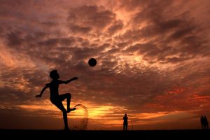 pexels-photo-978695-978695 A child playing soccer on the beach at sunset in Kochi, India, creating a striking silhouette against the vibrant sky.